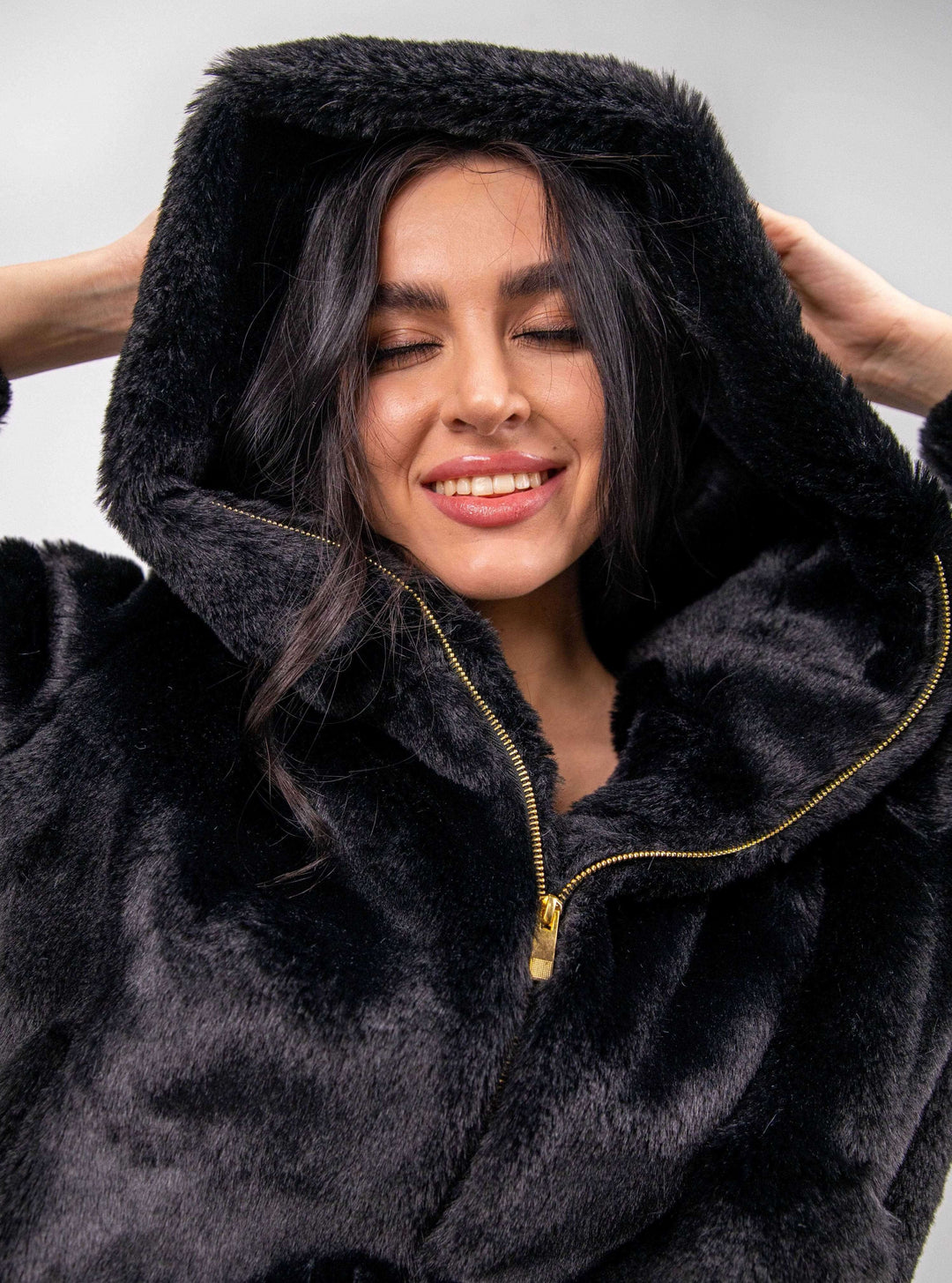 Woman smiling in a black faux fur zip-up hoodie, elegant winter fashion style
