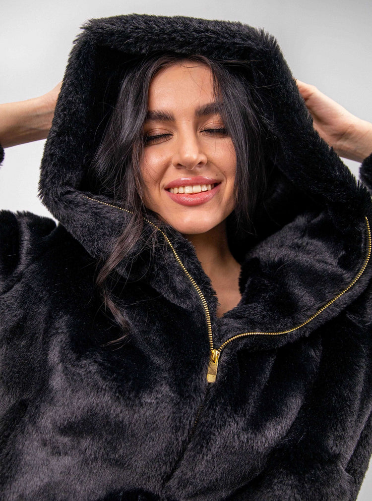 Woman smiling in a black faux fur zip-up hoodie, elegant winter fashion style