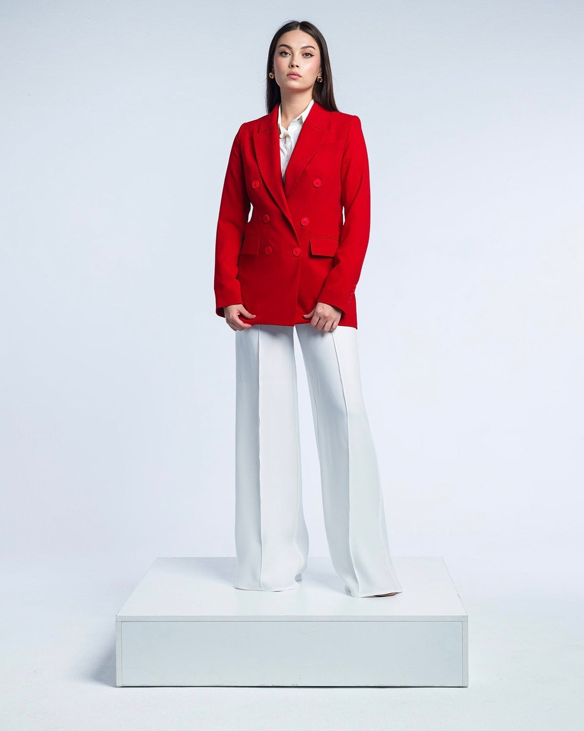 Woman wearing red double-breasted blazer and white wide-leg pants in studio setting