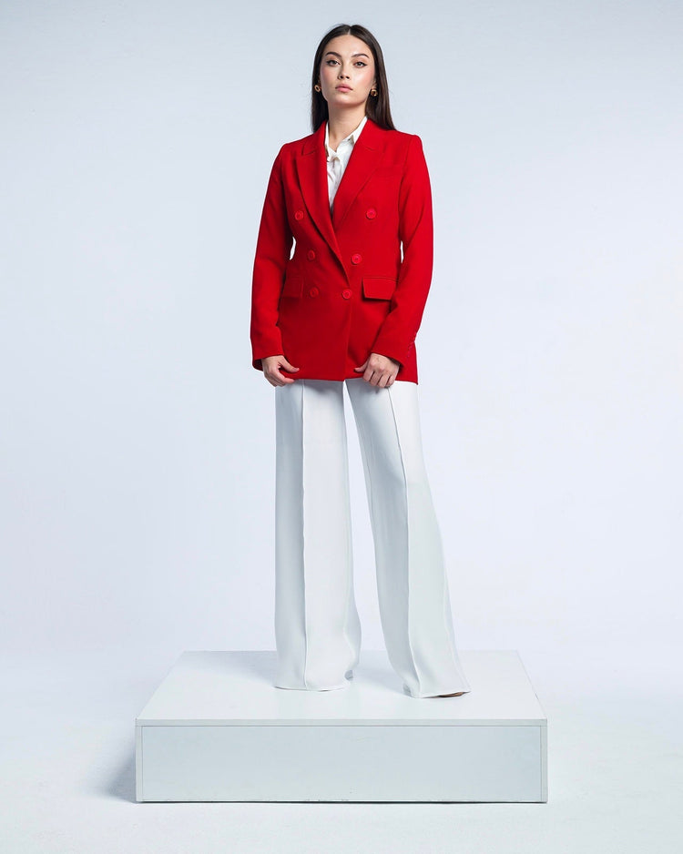 Woman wearing red double-breasted blazer and white wide-leg pants in studio setting