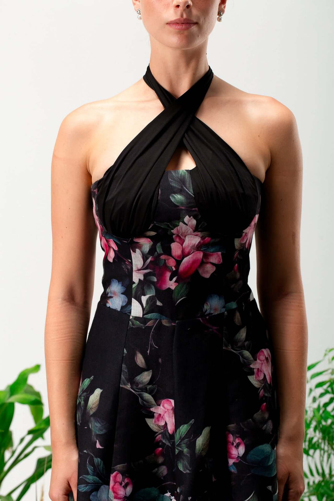 Woman wearing a sleeveless black floral halter neck dress with crisscross bodice