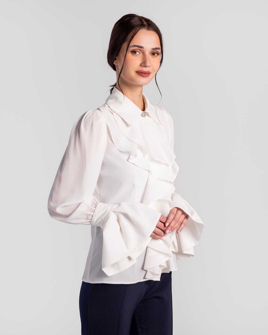 Elegant woman wearing a white ruffled blouse with dramatic flared sleeves and dark pants