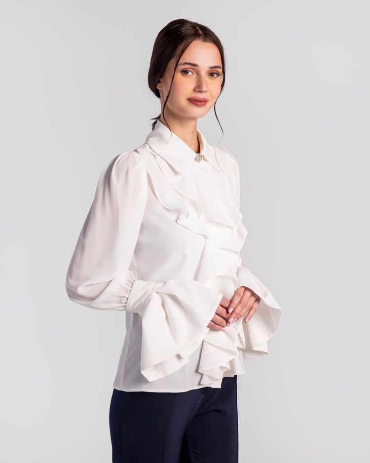 Elegant woman wearing a white ruffled blouse with dramatic flared sleeves and dark pants