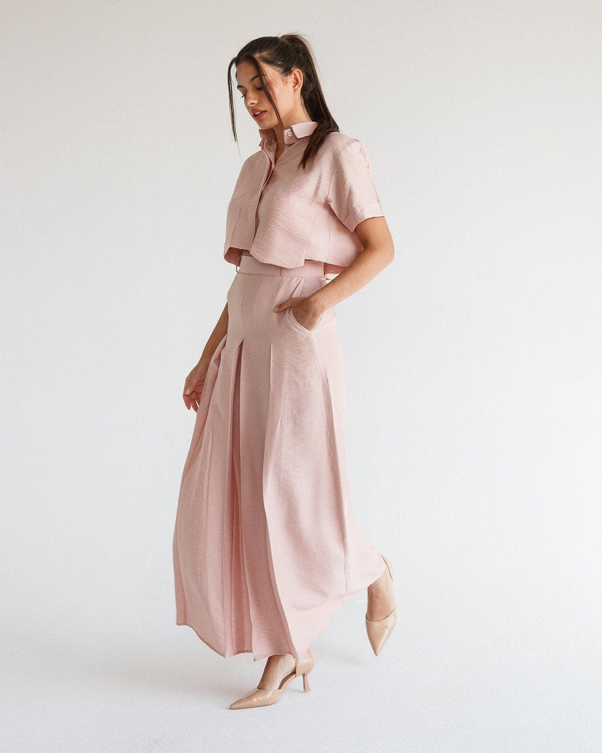 Woman in a blush pink flowy two-piece set with collared crop top and wide-leg pants