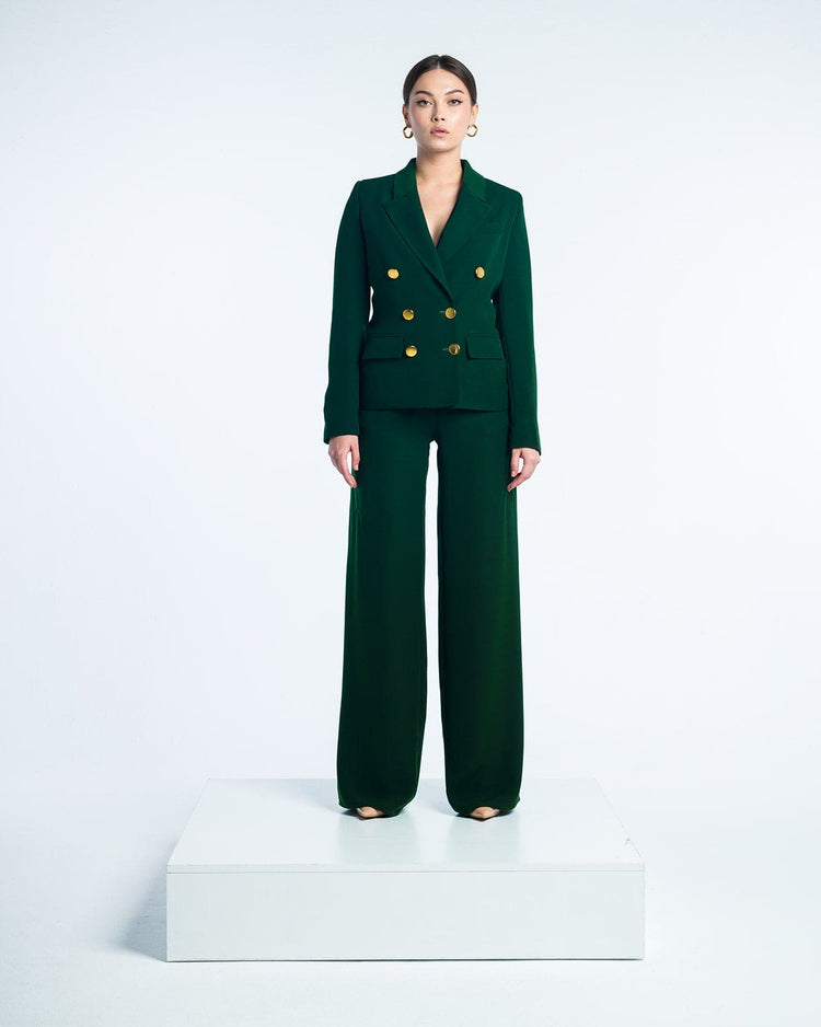 Woman in elegant dark green double-breasted suit with gold buttons and wide-leg pants