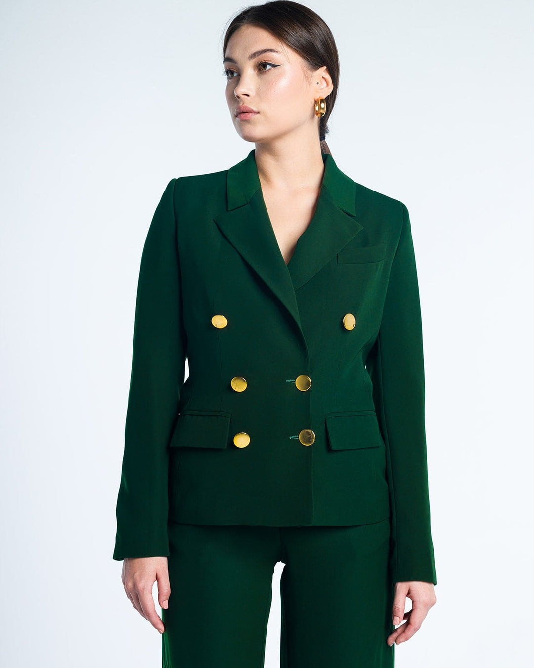 Woman wearing elegant dark green double-breasted suit with gold buttons, fashion outfit