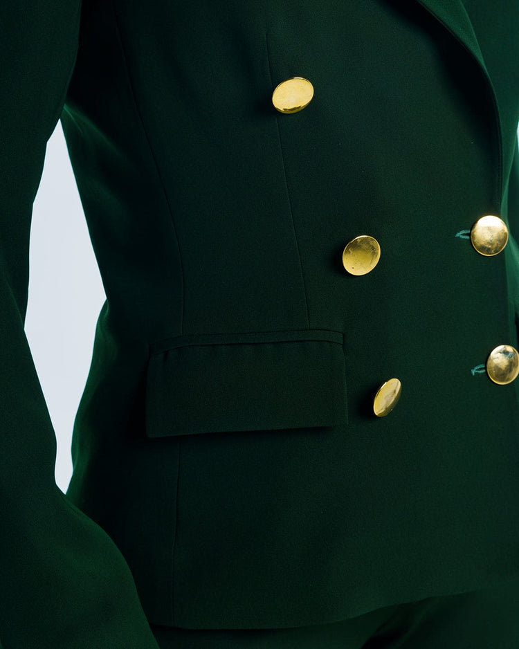 Close-up of tailored dark green blazer with gold buttons and a flap pocket