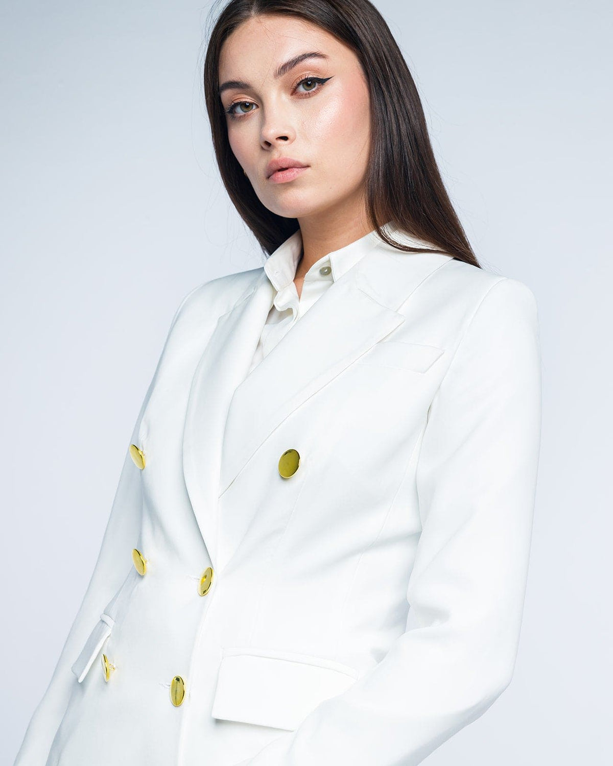 Woman wearing a white double-breasted blazer with gold buttons, elegant fashion style
