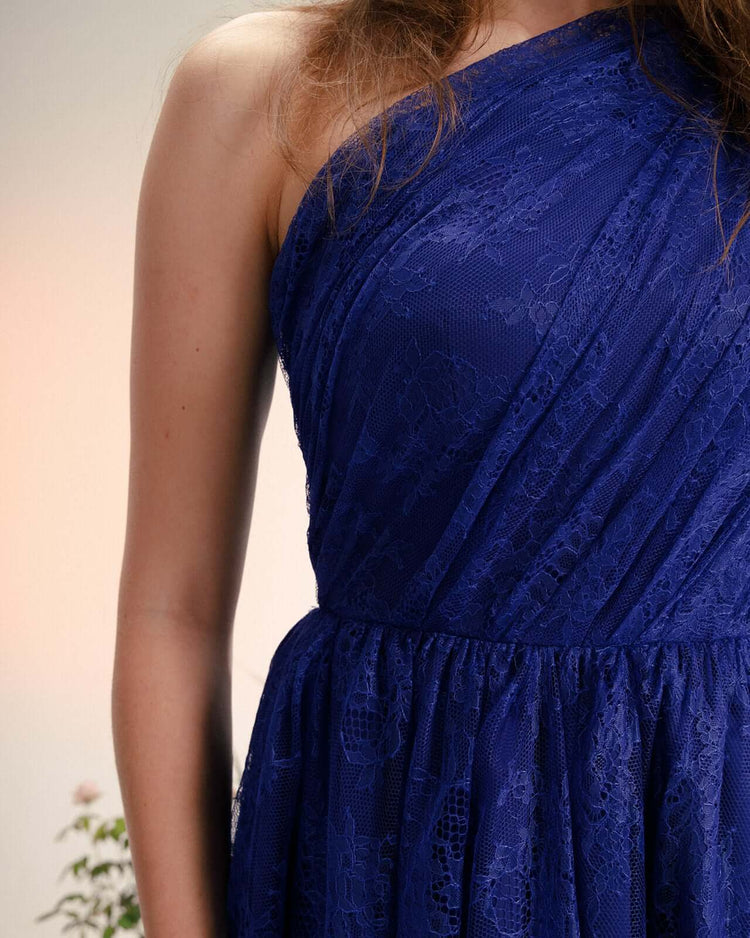 Woman wearing elegant one-shoulder blue lace dress, close-up on fabric detail