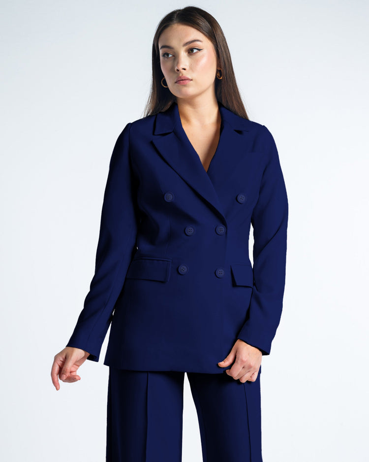 Woman wearing a navy double-breasted suit jacket and matching pants against white background