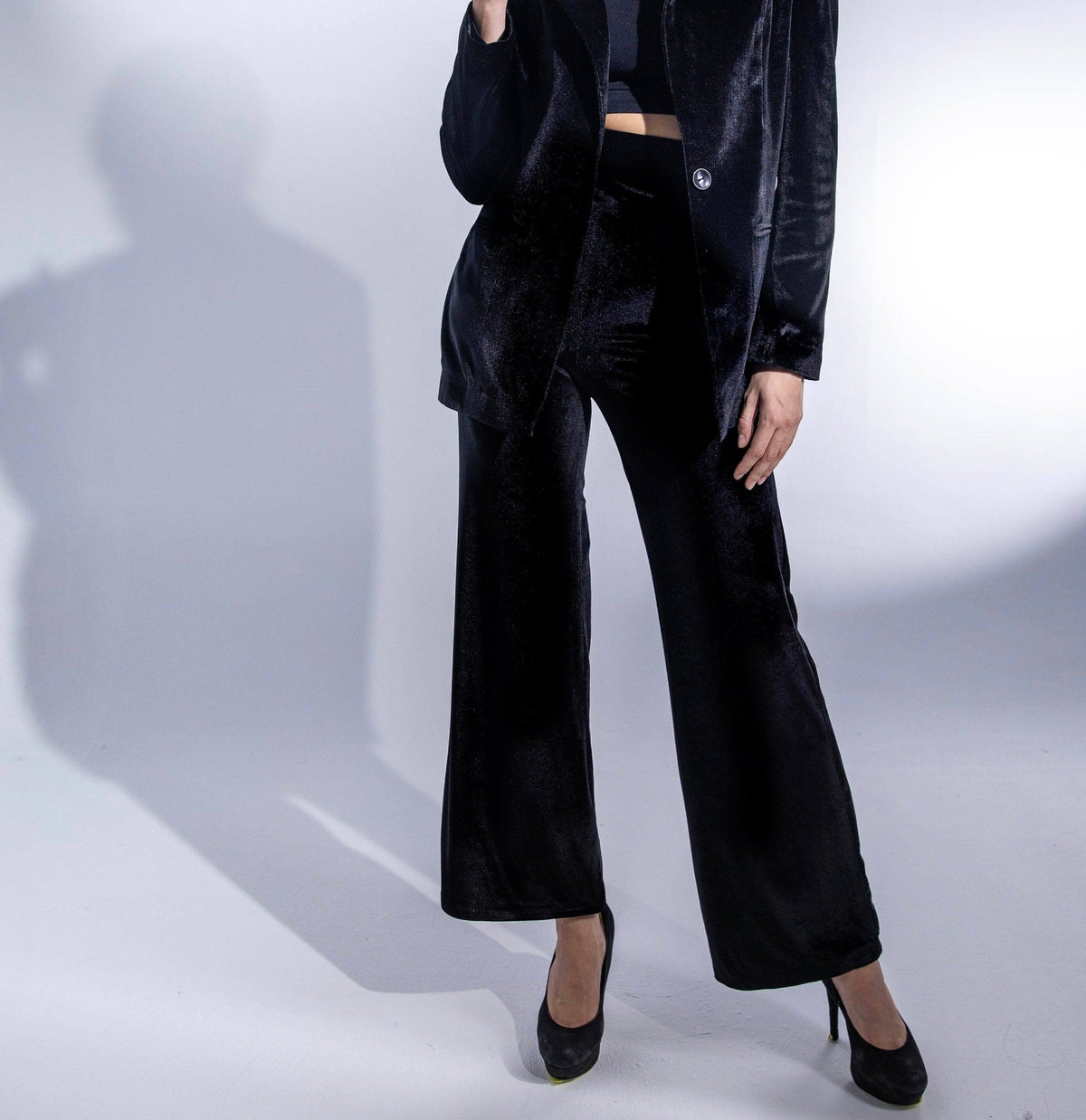 Woman wearing a black velvet pantsuit with wide-leg trousers and high heels