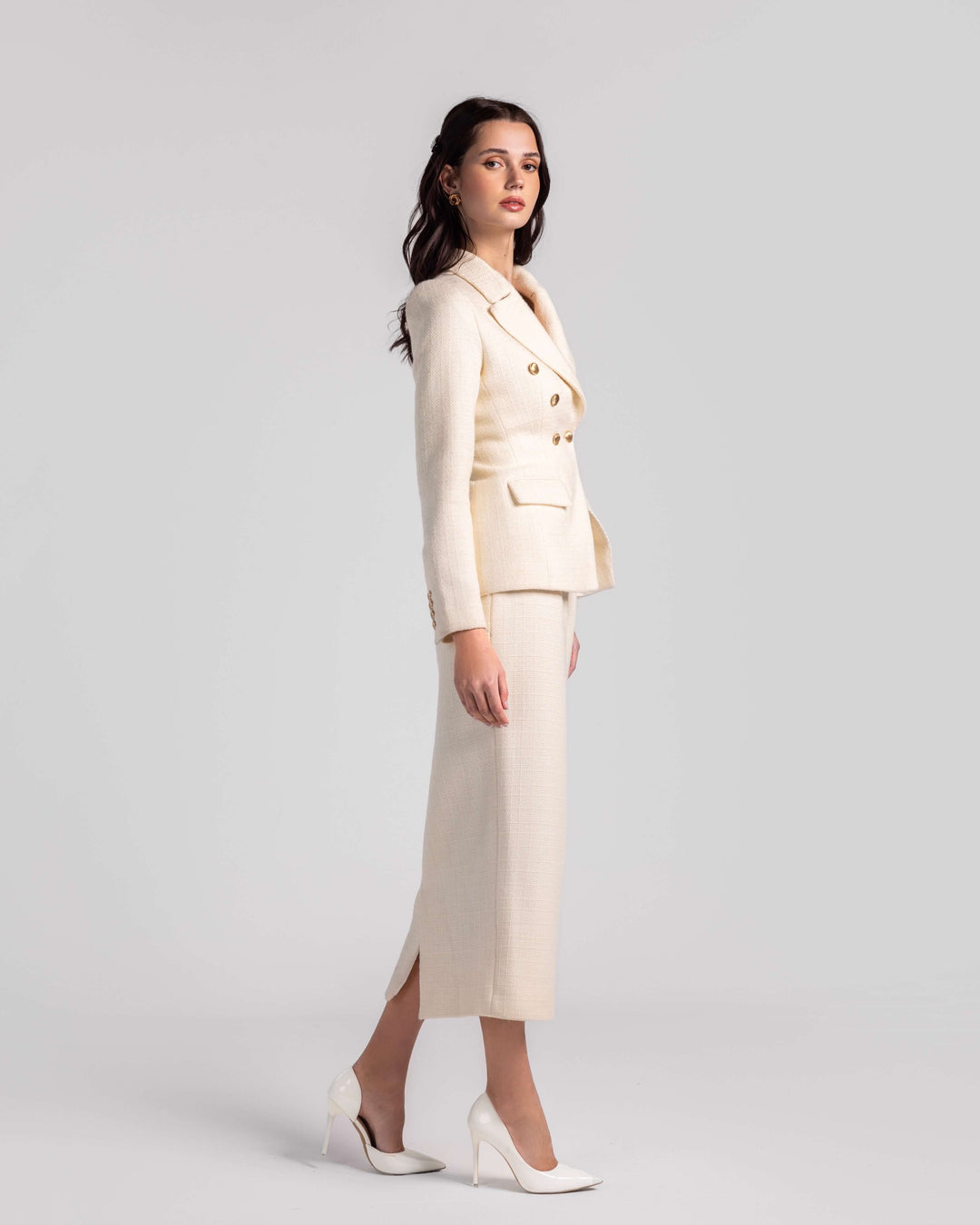 Woman wearing cream double-breasted blazer and matching skirt set with white heels