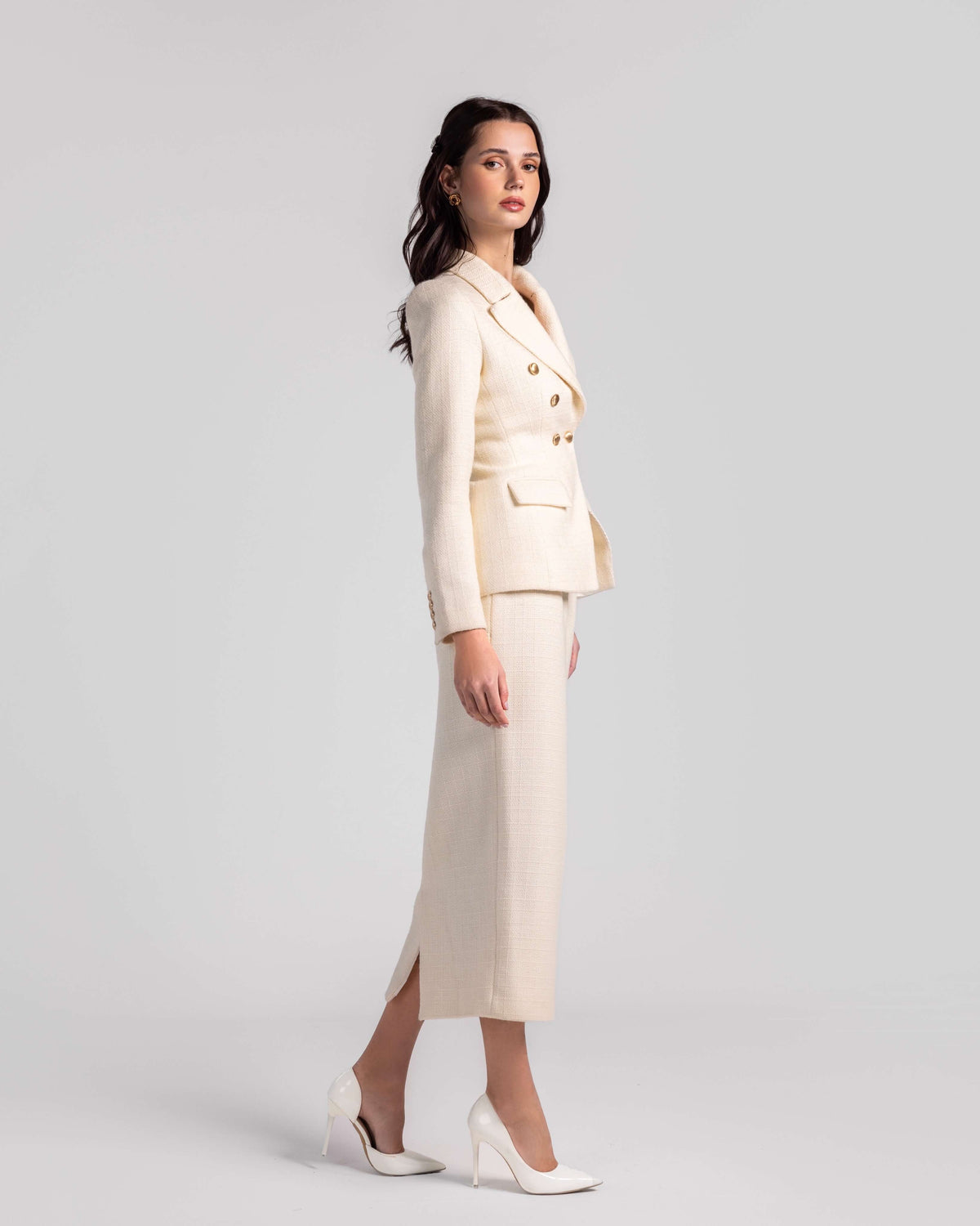 Woman wearing cream double-breasted blazer and matching skirt set with white heels