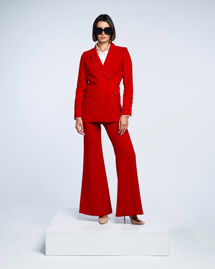 Woman in stylish red suit with flared pants, white shirt, nude heels, and black sunglasses